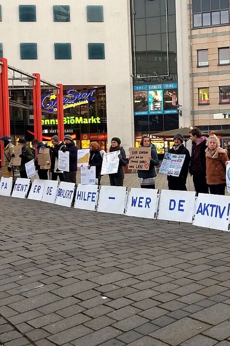Menschen stehen in einer Reihe und halten Plakate vor sich Menschen stehen in einer Reihe und halten Plakate vor sich