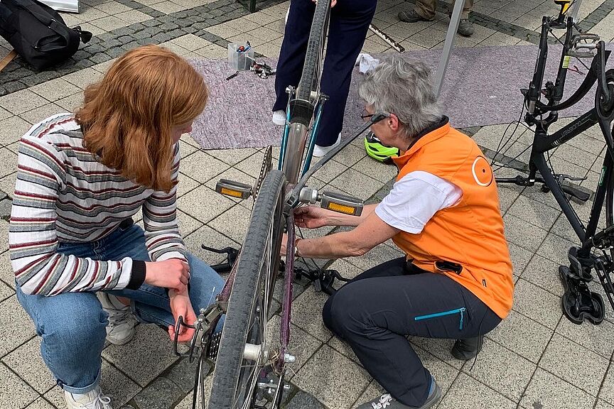 2023_05_05 Campusrepariertag 4 Eine Frau vom ADFC und eine Studierende arbeiten an einem Fahrrad