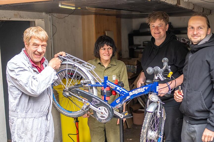 Freiwilligentag Bürgerstiftung Jena 2026 - Aktion ADFC Selbsthilfewerkstatt Vier Männer halten ein kaputtes Kinderfahrrad hoch