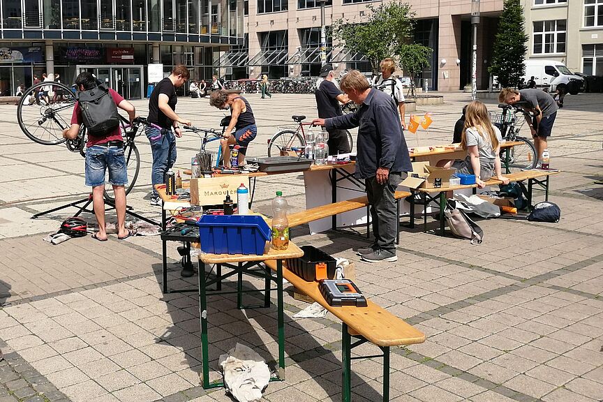 Campus-Reparaturtag Sommersemester 2026 auf einem Platz reparieren mehrere Menschen Fahrräder