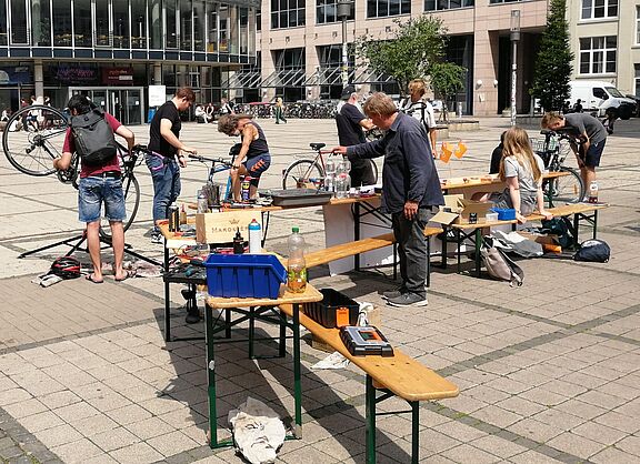 auf einem Platz reparieren mehrere Menschen Fahrräder
