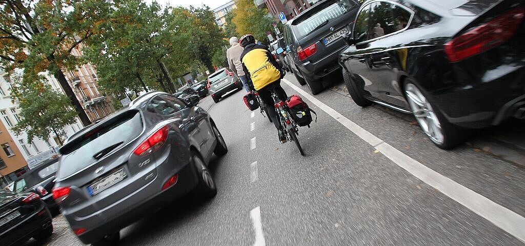 Ein Radfahrer auf einem Schutzstreifen wird mit weniger als 1,5 m Abstand überholt.