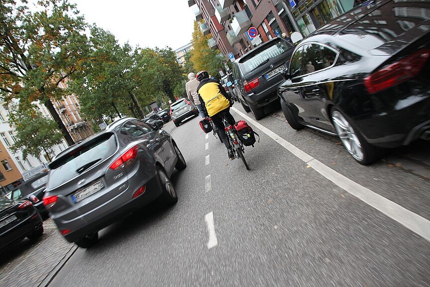 Ein Radfahrer auf einem Schutzstreifen wird mit weniger als 1,5 m Abstand überholt.