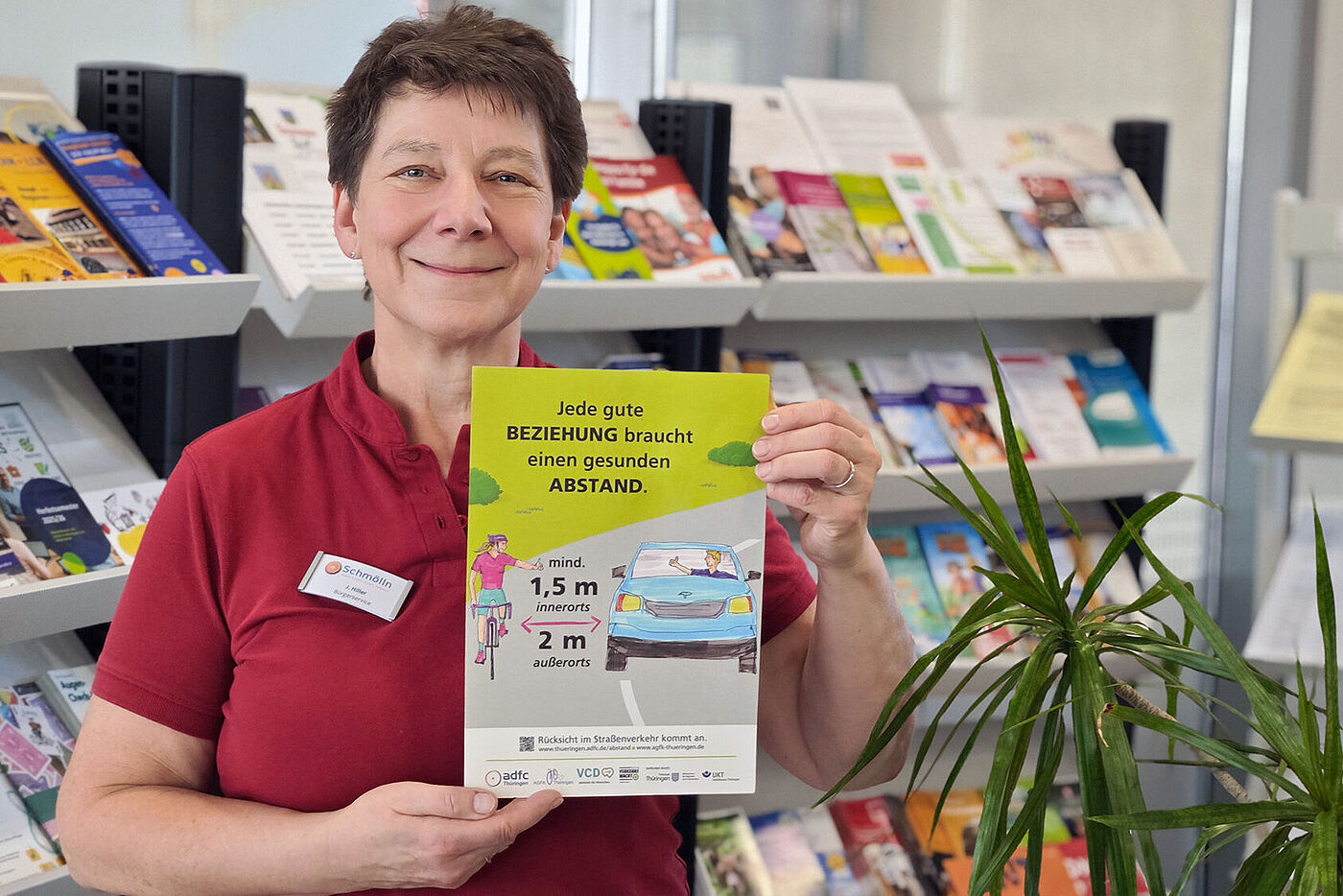 28.10.2025: Im Bürgerservice Schmölln hält eine Mitarbeiterin ein Plakat der Abstandskampagne hoch.