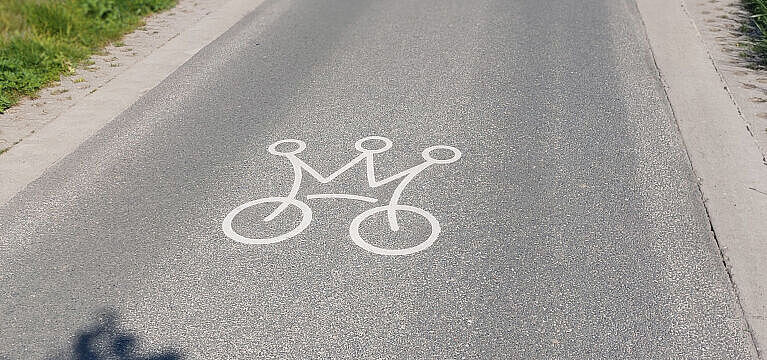 Straßenoberfläche, auf der ein gekröntes Fahrrad als Icon abgebildet ist.