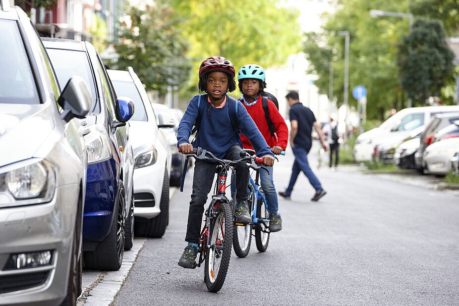 Kinder fahren auf der Straße Zwei Kinder fahrne hintereinander
