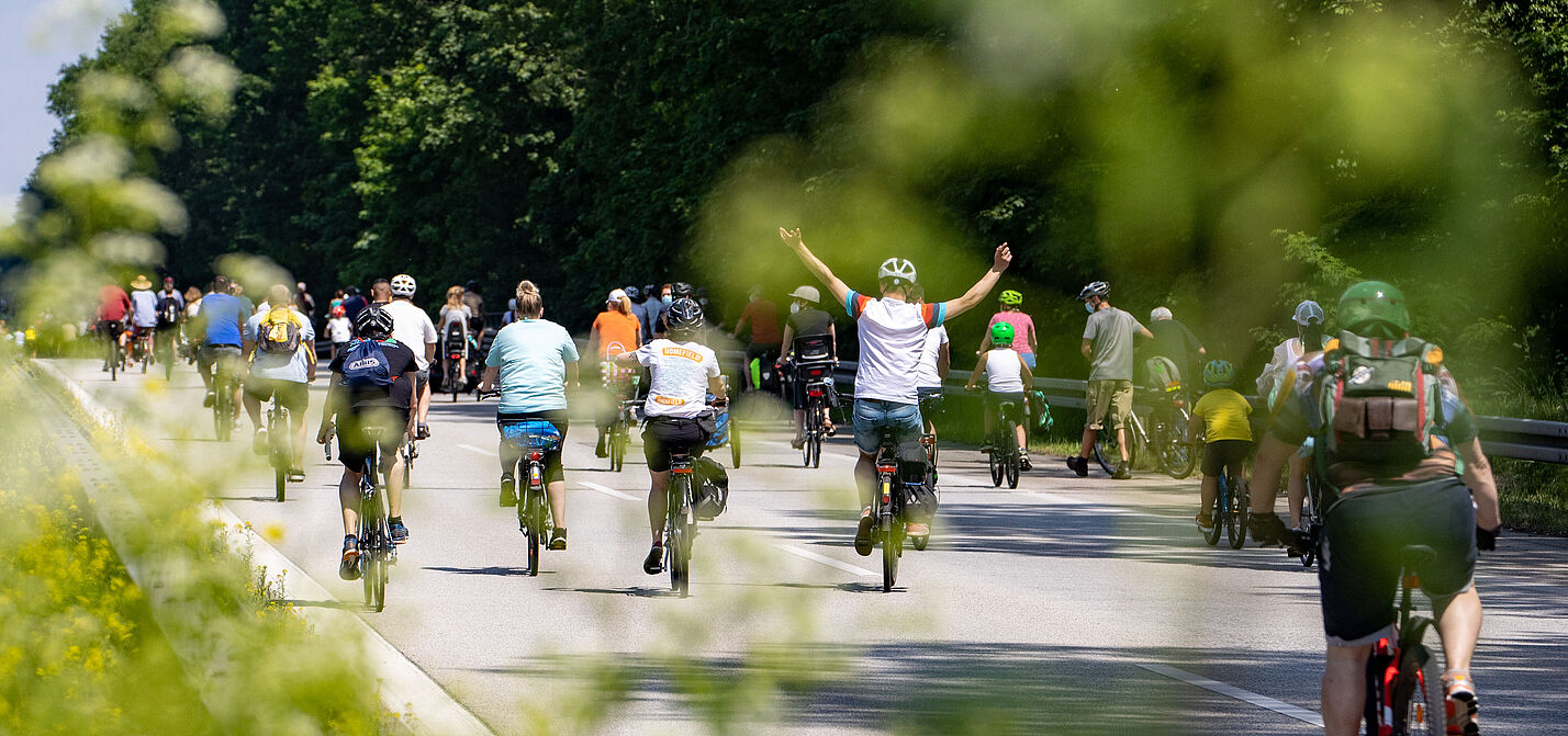 Radfahrer bei Sternfahrt neben Schild zu Geschwindigkeitsbegrenzung 100h/km