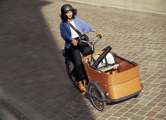 Aktionsbild der Aktion "Mit dem Rad zur Arbeit" von ADFC und AOK. Eine Frau fährt mit einem Lastenrad.