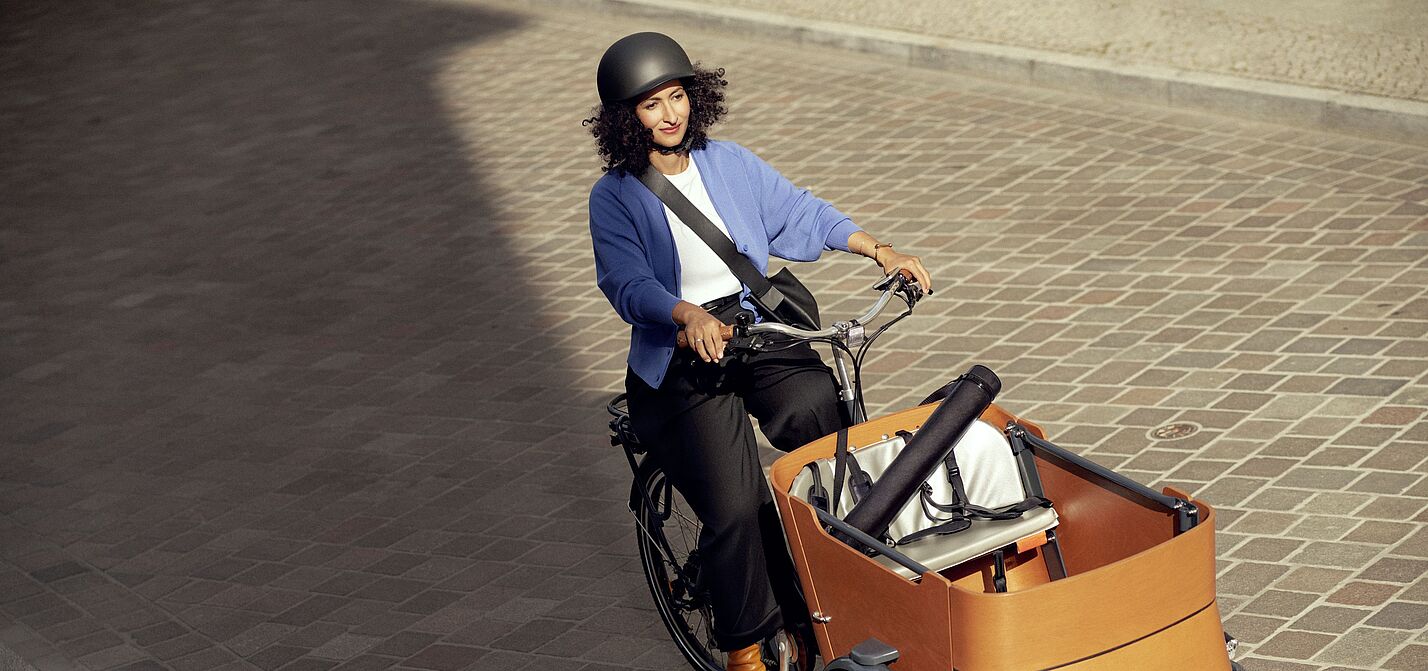 Aktionsbild der Aktion "Mit dem Rad zur Arbeit" von ADFC und AOK. Eine Frau fährt mit einem Lastenrad.